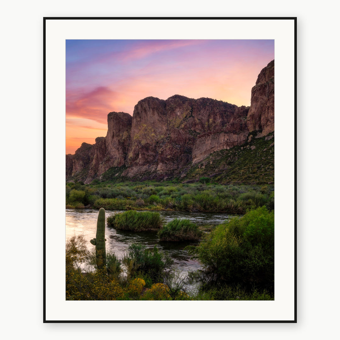 Arizona river, saguaro cactus and cliffs beneath a pastel sunrise, shown with a white mat and thin black frame.